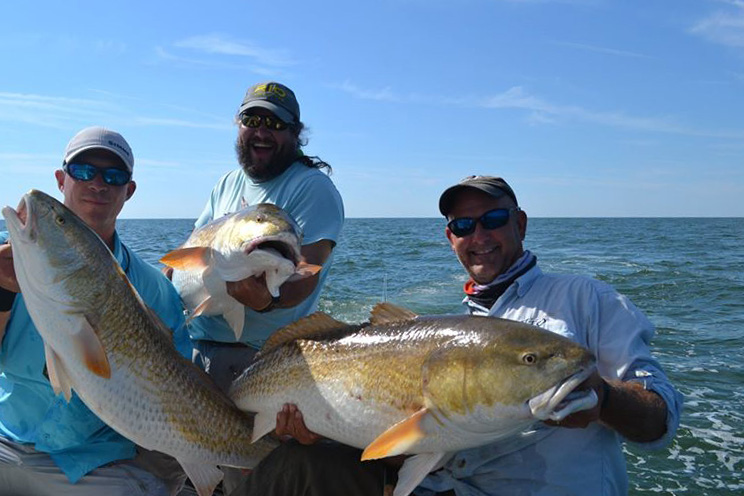 anglers holding large fish on a fishing boat
