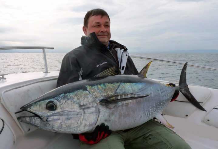 A tired angler holding holding a large Tuna caught while giant Bluefin Tuna fishing in the Outer Banks