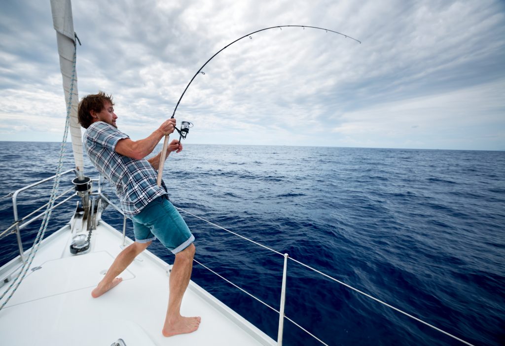 un pescador luchando contra un pez desde un bote