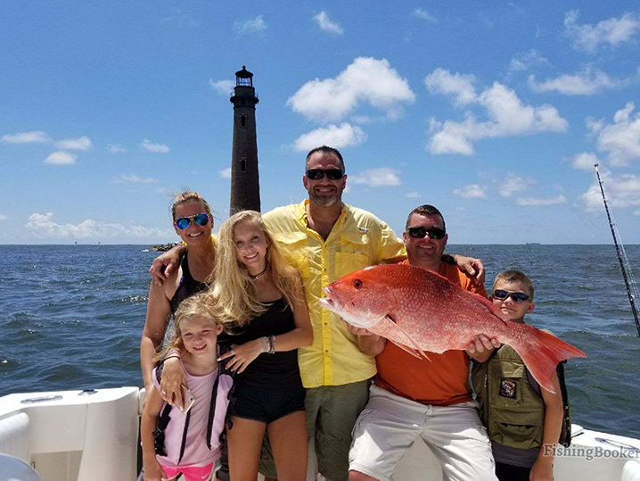 Uma família com capitão de fretamento mostrando o Red Snapper que apanharam a pescar fora da ilha de Dauphin.
