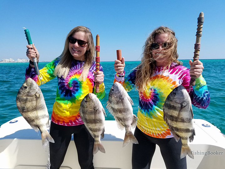 Two girls in colorful shirts holding Black Drum on a family fishing trip out of Destin, FL.
