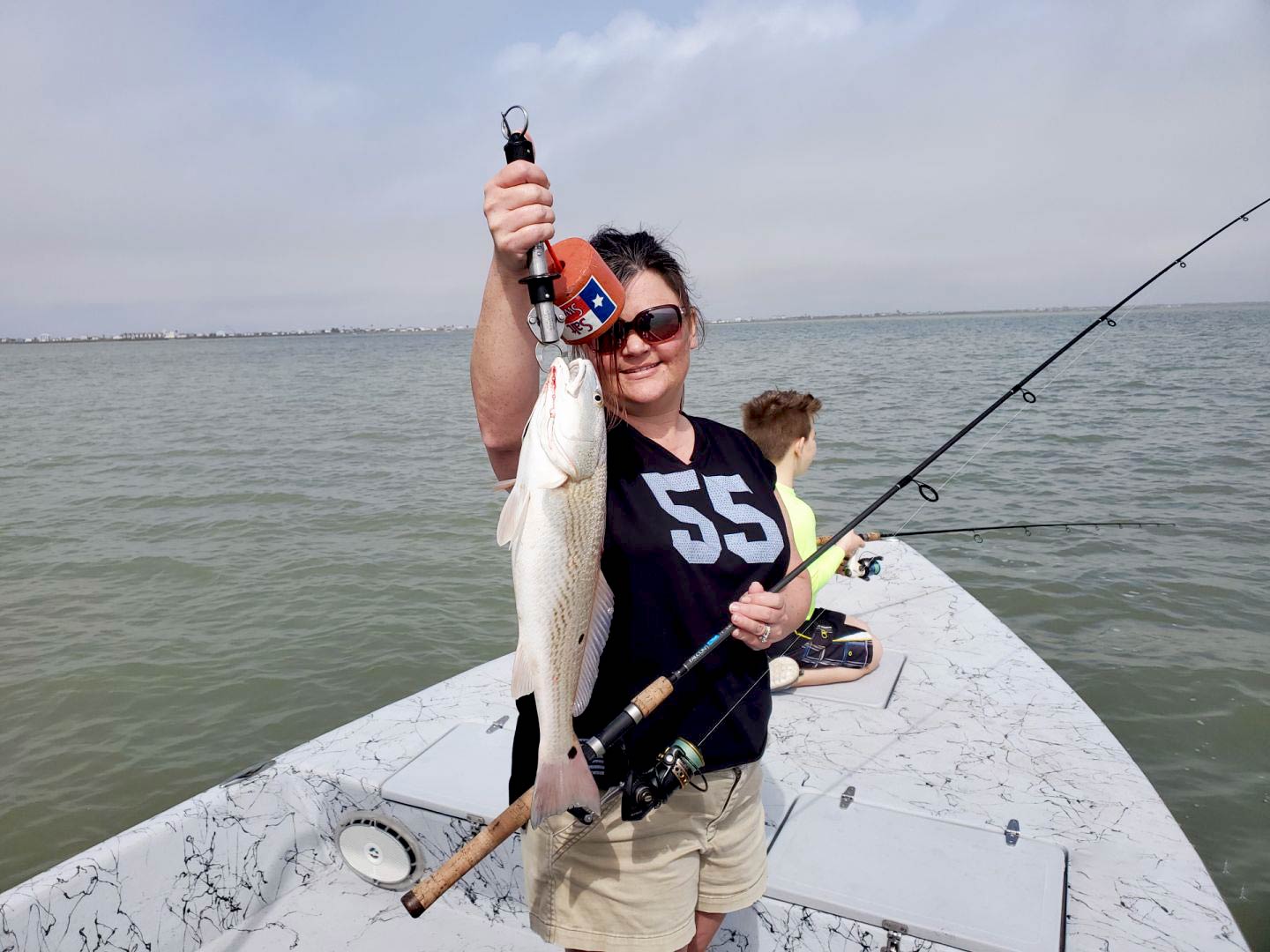 Una mujer sujetando una gallineta en un barco mientras pesca con su hijo en la bahía de Matagorda