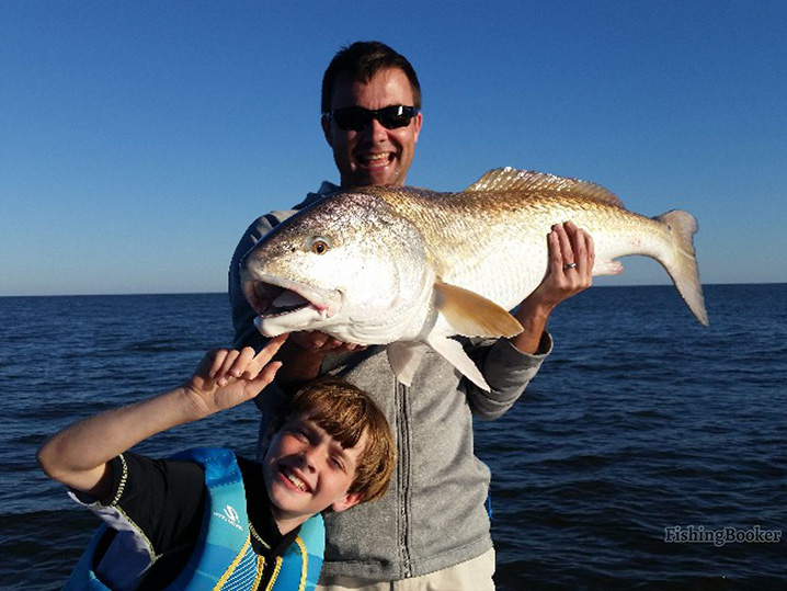 A dad and his son holding Redfish which they caught on a fishing trip in Savannah, Georgia.