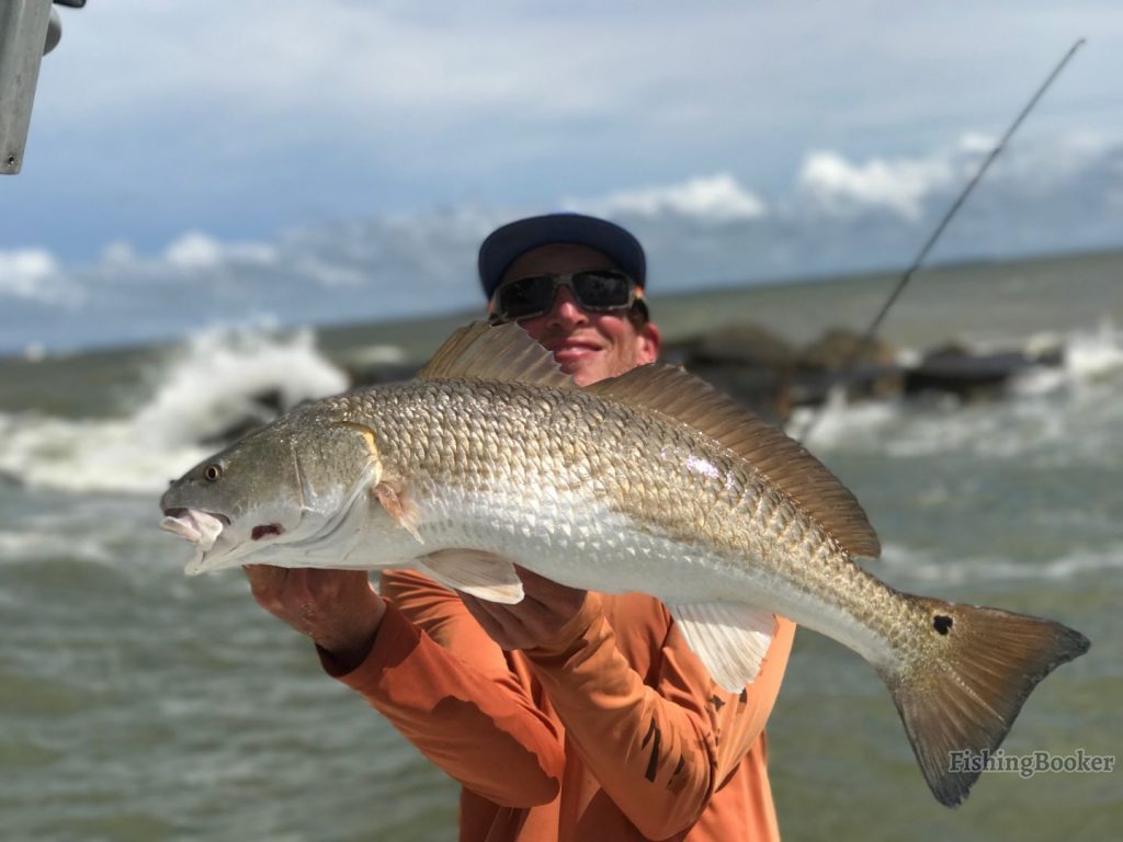 Angler holding a big Redfish he caught in Galveston.
