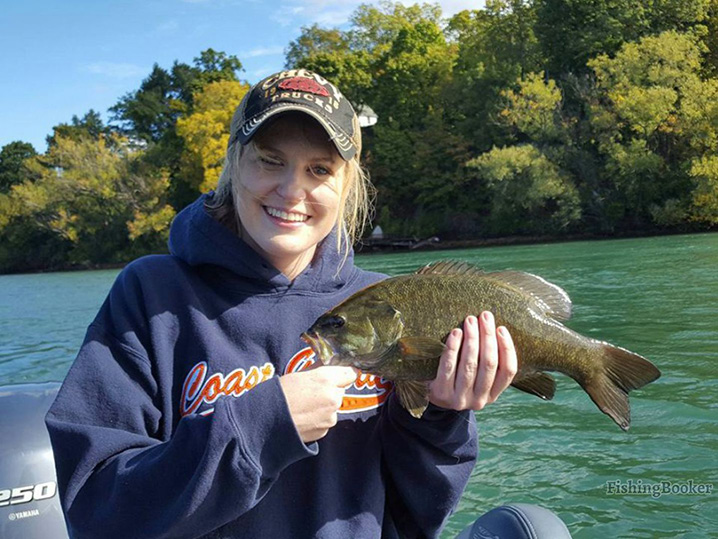 A smiling girl holding a fish she caught in the Presque Isle State Park.