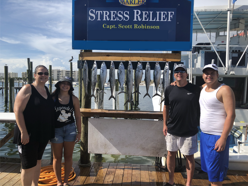 a family of four posing at the dock next to the fish they caught on a fishing charter, showing that fishing is a great guilt-free activity to enjoy during the covid pandemic